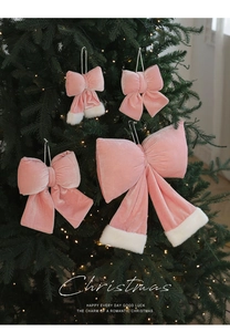 Détail de quatre nœuds de Noël en velours rose avec bordure en fourrure sur un sapin