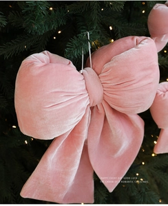 Détail d'un nœud de Noël en velours rose avec texture pelucheuse sur branche verte