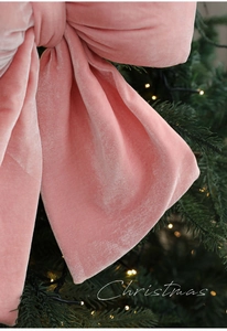 Gros plan d'un grand nœud de Noël en velours rose montrant la texture douce du tissu soyeux