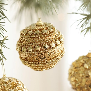 Luxurious gold Christmas ball with sparkling stars and beads on a festive tree