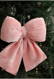 Détail d'un nœud de Noël en velours rose avec cordelette sur un sapin illuminé