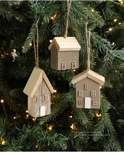 Detailed view of three mini wooden Christmas house ornaments hanging on a festive tree