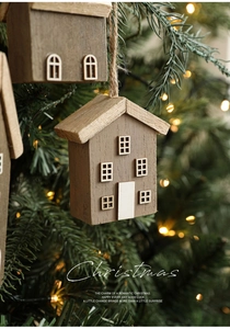 Detail of wooden Christmas house ornament hanging on tree with warm festive lights