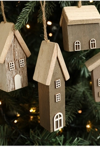 Detail of wooden Christmas house ornaments with white window accents on pine branch