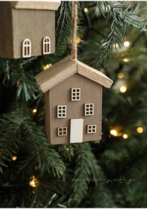 Detail of wooden house ornaments on Christmas tree with warm lights and natural wood grain