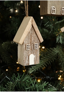 Close-up of rustic wooden Christmas house ornament with twine loop on a green tree
