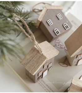 Detail of wooden Christmas house ornament with twine loop on soft pine branch