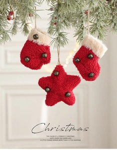 Close-up of red plush Christmas ornaments with bells hanging on green pine branches