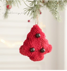 Detail showing a red plush Christmas tree ornament with metal bells and rustic twine hanger