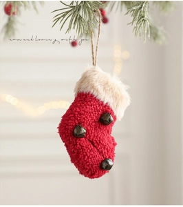 Close-up of red plush Christmas stocking with white fur trim and vintage copper bells