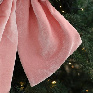 Nœud de Noël en velours rose sur un sapin vert festif avec lumières chaudes