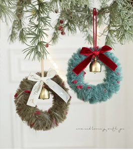 Detail of plush Christmas wreaths with gold bells and velvet ribbons on pine branches