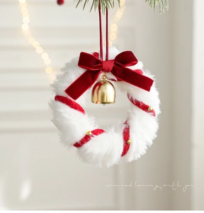 Detail of plush Christmas wreath with red velvet bow, gold bell, and festive red ribbons