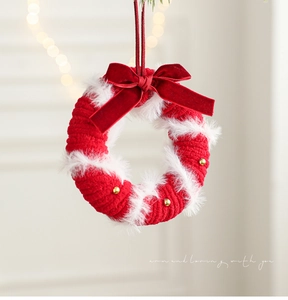 Close-up of red and white plush Christmas wreath with velvet bow and golden bells