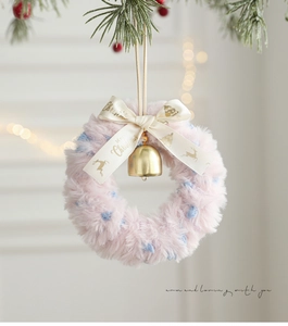 Close-up of plush Christmas wreath with satin ribbon, golden bell, and festive patterns