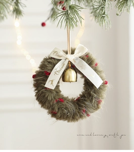 Detail of plush Christmas wreath with red berries, gold bell, and silk bow decoration