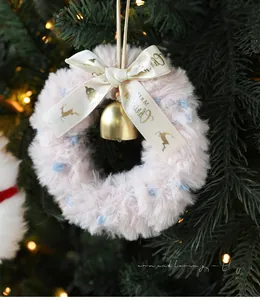 Close-up of pink plush Christmas wreath with golden bell and Merry Christmas silk bow
