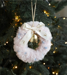 Detailed view of pink plush Christmas wreath with gold bell and Merry Christmas ribbon