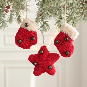 Red plush Christmas ornaments set with stars and socks hanging on snowy pine branches