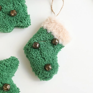 Chaussette de Noël en peluche verte avec cloches et fausse fourrure sur fond blanc