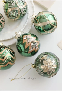 Detail of green Christmas balls with golden glitter patterns and hand-painted sequins