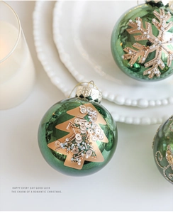 Macro shot of dark green Christmas bauble with gold glitter tree patterns and sequins
