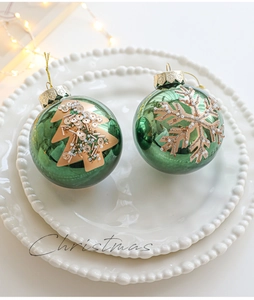 Detailed close-up of green Christmas ball ornaments with gold hand-painted patterns
