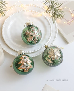 Detailed view of green Christmas ornaments with gold glitter patterns on white plates