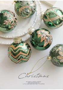 Macro detail of green Christmas baubles with golden glitter snowflakes and festive patterns