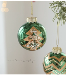 Detail of emerald green glass Christmas bauble with gold sequin tree patterns