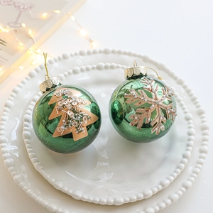 Green Christmas ornaments with gold sequin embroidery and silver caps in a white bowl