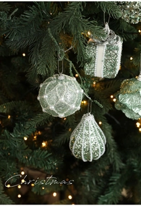 Close-up of mint green glitter Christmas ornaments with pearl details on a tree
