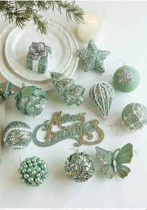 Flat lay of mint green Christmas ornaments with glitter details and festive pine decor