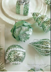 Close-up of green glitter Christmas ornaments in pine cone, tree, and gift box shapes