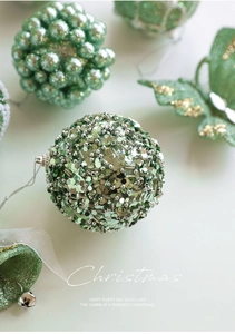 Close-up of light green sequined Christmas balls and beaded butterfly ornaments