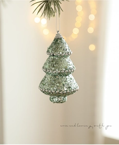 Detail of green glitter Christmas tree ornament with silver beads on a festive branch