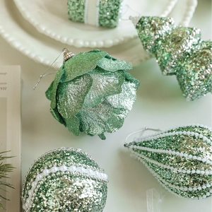 Sparkling light green Christmas ornaments set with pinecones, trees, and globes