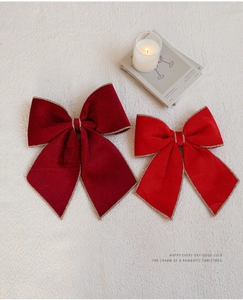 Dettaglio di fiocchi natalizi in velluto rosso e bordeaux con bordi dorati glitterati