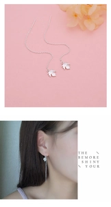 Macro detail of S925 sterling silver maple leaf tassel earrings on a soft pink background