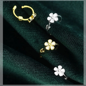 Detailansicht der Gänseblümchen-Ohrringe mit weißen Emaille-Blüten auf Gold- und Silberreifen