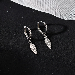 Detailed view of S925 sterling silver hoop earrings with fine feather pendants on black fabric