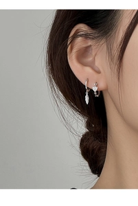 Close-up of silver leaf pendant earring and heart-shaped hoop with pavé zircon stones