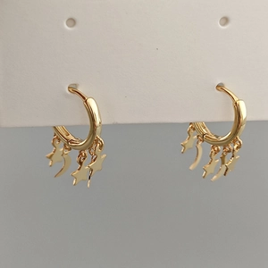 Elegant gold hoop earrings with star and moon tassels hanging on a display card