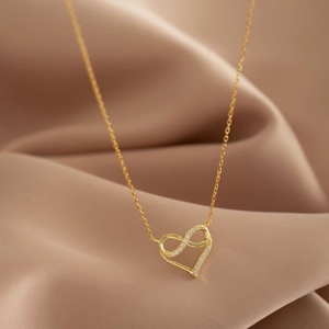 Collier cœur infini doré élégant avec diamants brillants sur fond de satin champagne