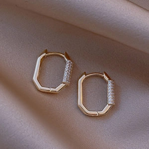Elegant gold octagonal hoop earrings with sparkling cubic zirconia on silk background