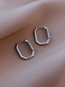 Close-up of silver octagonal hoop earrings with micro-inlaid zircon on silk background