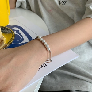 Close-up of elegant pearl bracelet with silver rectangular links worn on wrist
