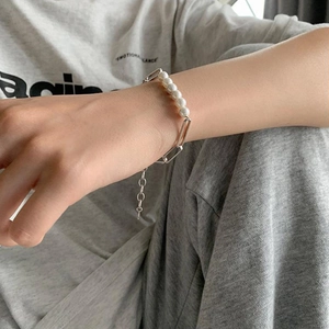 Detail of elegant pearl and rectangle link chain bracelet worn on a female wrist
