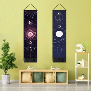 Détail de tapisseries bohèmes soleil et lune avec franges noires sur mur vert clair