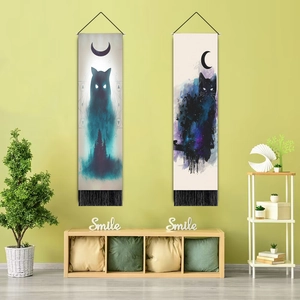 Close-up of artistic cat and moon wall tapestries with tassels in a cozy home setting